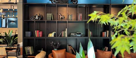 Un interno moderno con divani in pelle, una libreria con libri e oggetti decorativi, e una motocicletta in mostra.