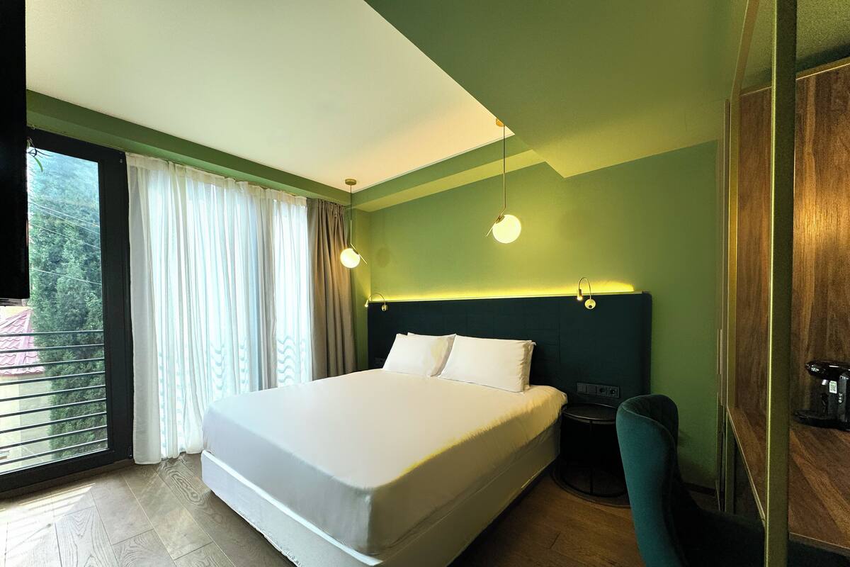 A modern hotel room with a large bed, a desk, and a chair.