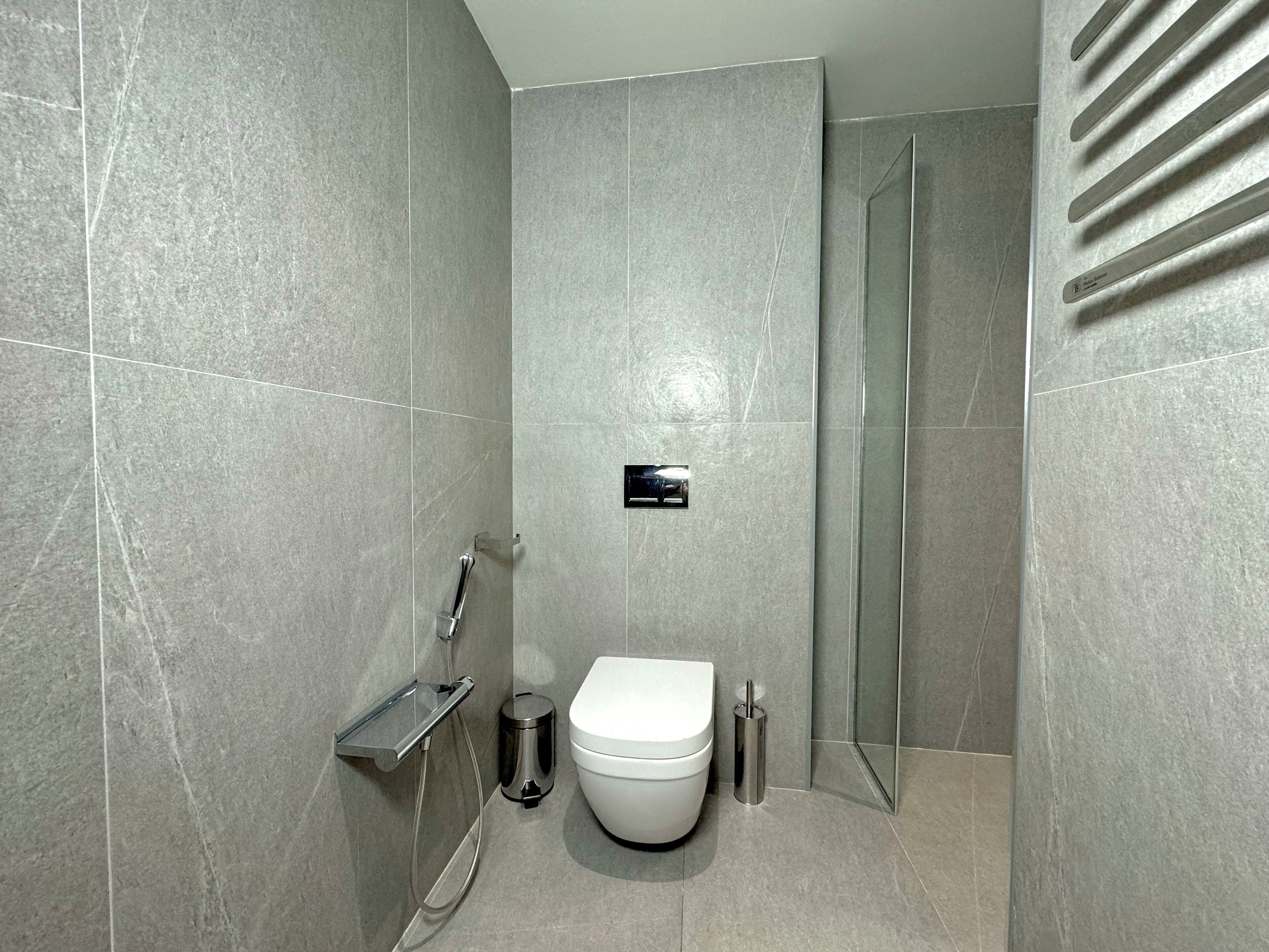 Une salle de bain moderne équipée de toilettes, d’une douche et d’un espace de douche clos par des parois de verre.