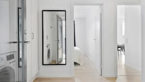 A modern hotel room with a large mirror, a bed, a desk, and a view of the city.