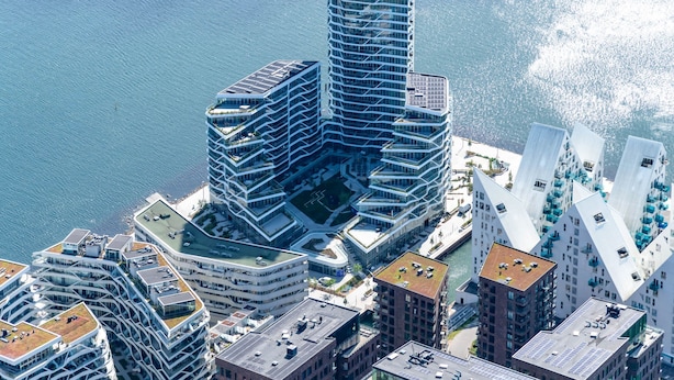 A high-rise building with a unique angular design, surrounded by other modern structures.