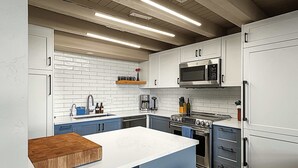 A modern kitchen with white cabinets, a central island, a built-in oven, and a microwave. - Vista Viewhaus Lodge (Steamboat Springs)
