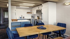 A modern kitchen with white cabinets, a wooden dining table, and blue chairs. - Vista Viewhaus Lodge (Steamboat Springs)