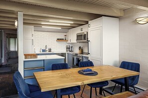 Une cuisine moderne avec des meubles blancs, une table à manger en bois et des chaises bleues.