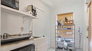 A compact kitchen with a microwave, coffee maker, and a metal rack with dishes. - Cozy Tiny Home for Couples Near Lafayette Hotspots (Lafayette)
