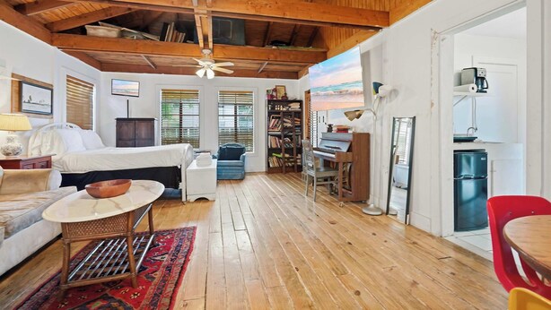 A cozy room with a bed, a small table, a chair, a bookshelf, and a kitchen area. - Cozy Tiny Home for Couples Near Lafayette Hotspots (Lafayette)