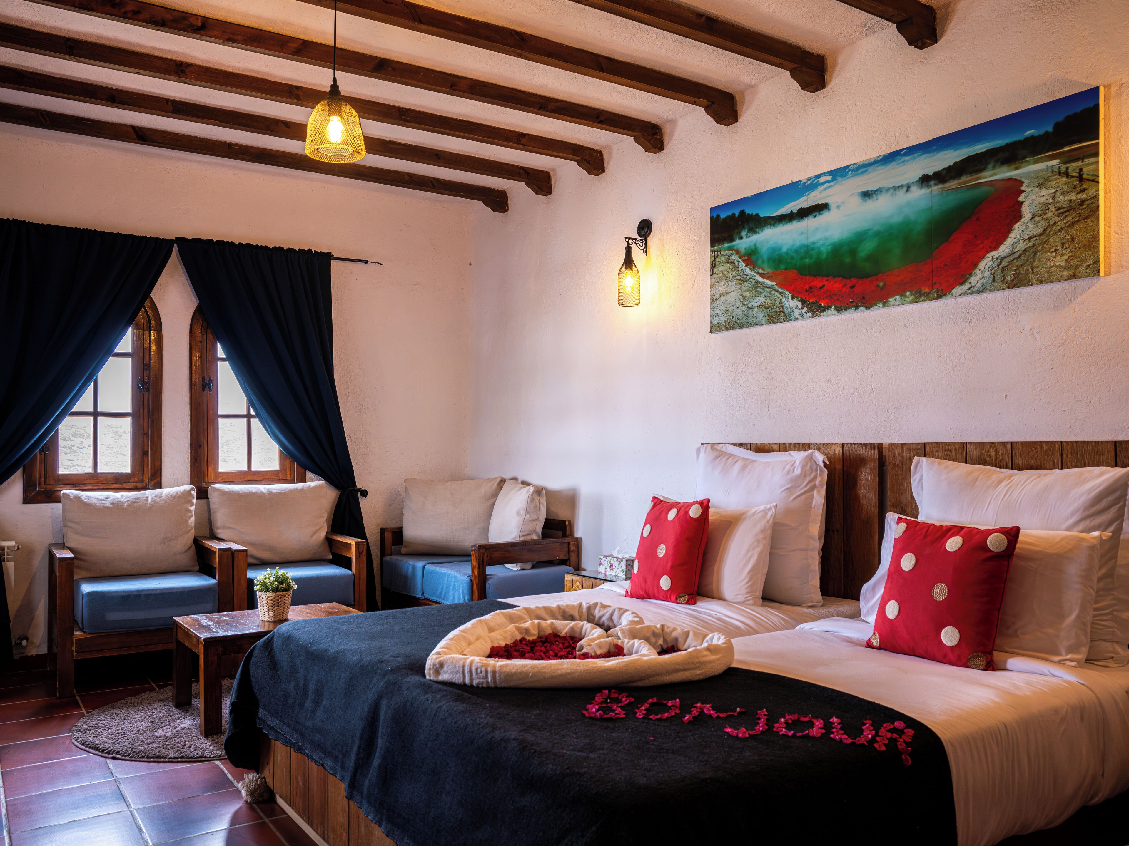 Una habitación acogedora con una cama, dos sillones, una mesita y un cuadro en la pared.