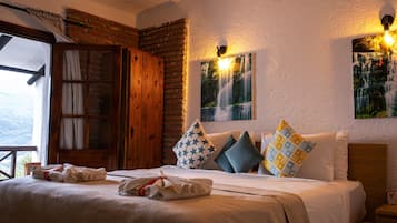 Une chambre d’hôtel avec un lit, des oreillers, une armoire en bois, une fenêtre et un tableau accroché au mur.