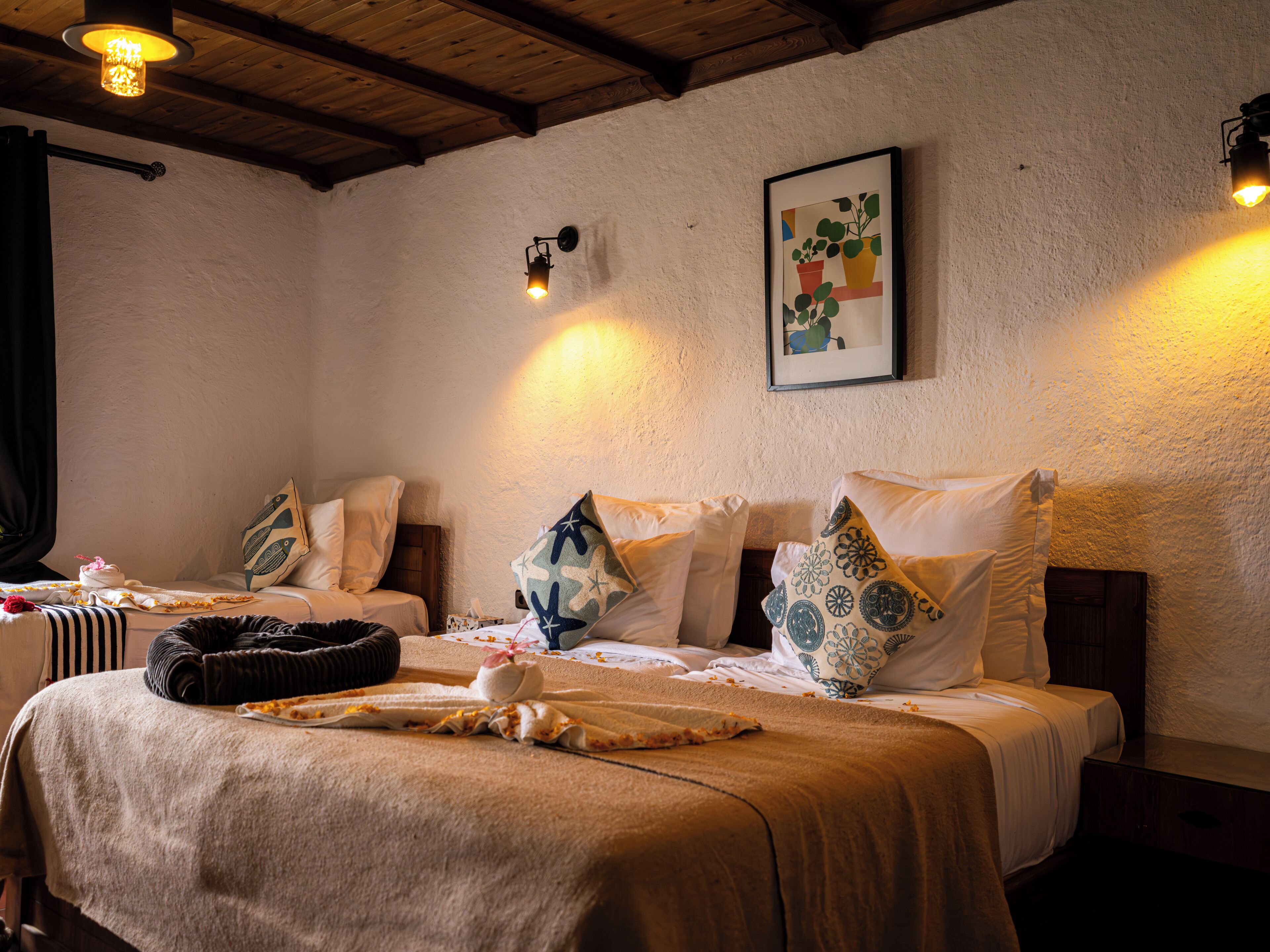 Een gezellige kamer met twee bedden, een houten plafond en een kunstwerk in een lijst aan de muur.
