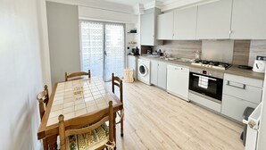 Een moderne keuken met een eettafel, stoelen, een wasmachine, een vaatwasser, een kookplaat en een spoelbak.