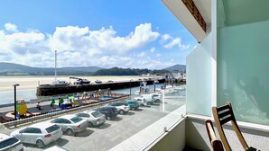 A view from a balcony overlooking a marina with parked cars and boats, a sandy beach, and mountains in the distance. - The Cliffs  A Ribeira - Polas (Foz)