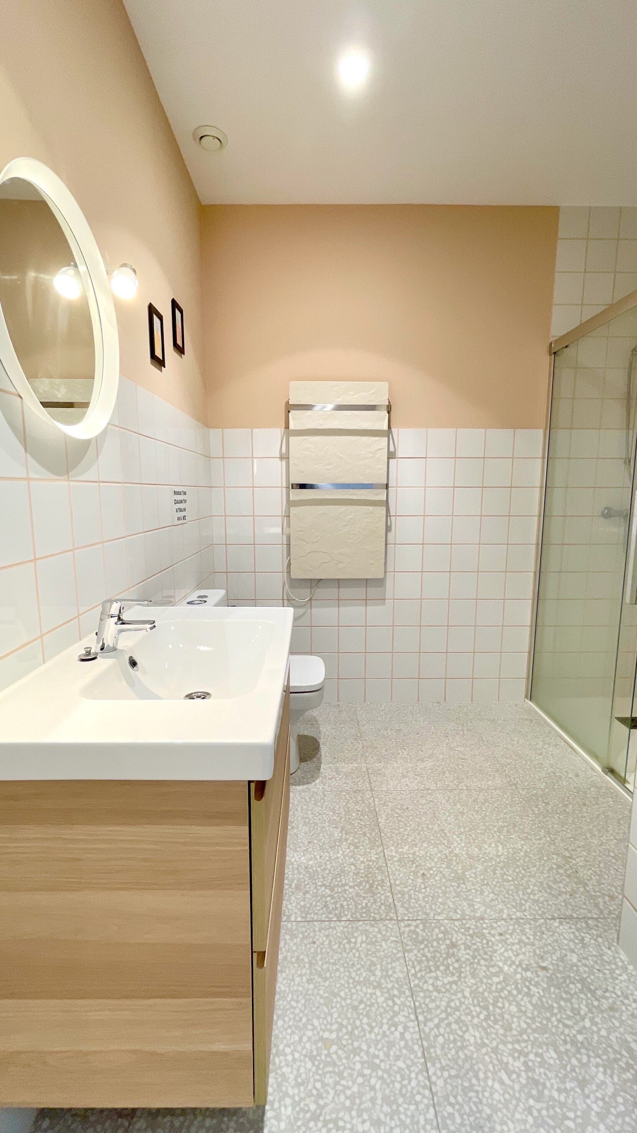A modern bathroom with a white sink, mirror, and toilet.