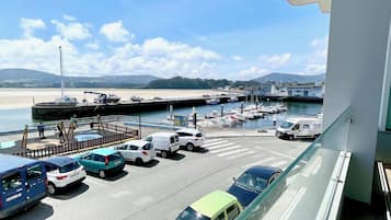 A marina with boats docked, a sandy beach, and a clear sky.