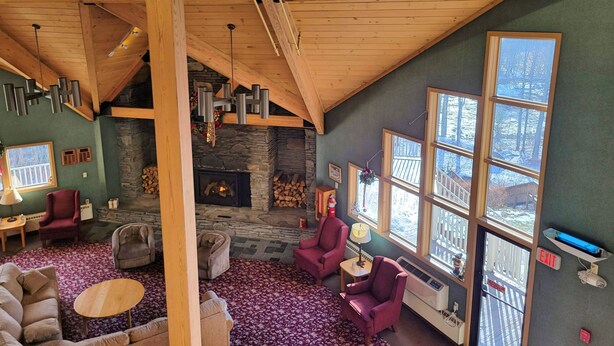 A cozy living room with a stone fireplace, wooden ceiling beams, and large windows offering a view of the outside. - Kitchen, AC, deck, mountain view, pool, ski shuttle. LB307 by LRS (Lincoln)