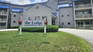A grey building with a sign reading "The Lodge Condominium Hotel". - Kitchen, AC, deck, mountain view, pool, ski shuttle. LB307 by LRS (Lincoln)