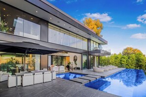 A modern house with a large glass facade, a swimming pool, and outdoor seating. - London Dream: Glamorous Sunset Strip Modern Compound with Theater, Pool & Spa (Los Angeles)
