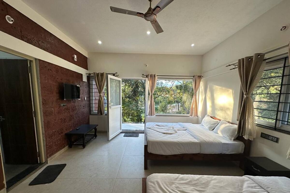 A bedroom with two beds, a ceiling fan, and a TV on the wall.