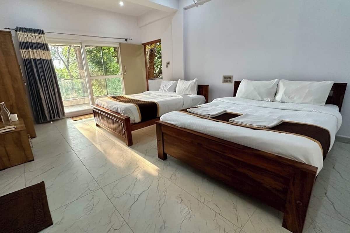 A bedroom with two beds, a wooden wardrobe, a window with curtains, and a tiled floor.