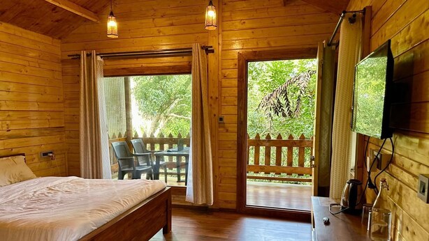 Una habitación tipo cabaña de madera con una cama, un escritorio y un televisor.