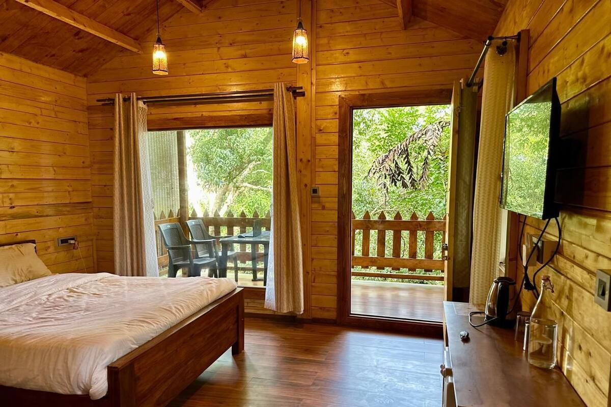 A wooden cabin room with a bed, a desk, and a television.