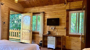 Una habitación de cabaña de madera con una cama, un escritorio con televisor y un calentador.