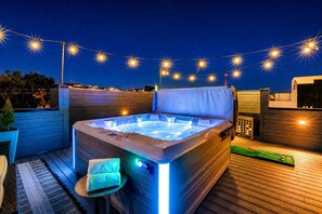 A hot tub on a wooden deck with string lights above, surrounded by a wooden fence and a pool table. - Nash Luxe Party! 13 Beds - Priv Hot Tub/Game Room! (Nashville)