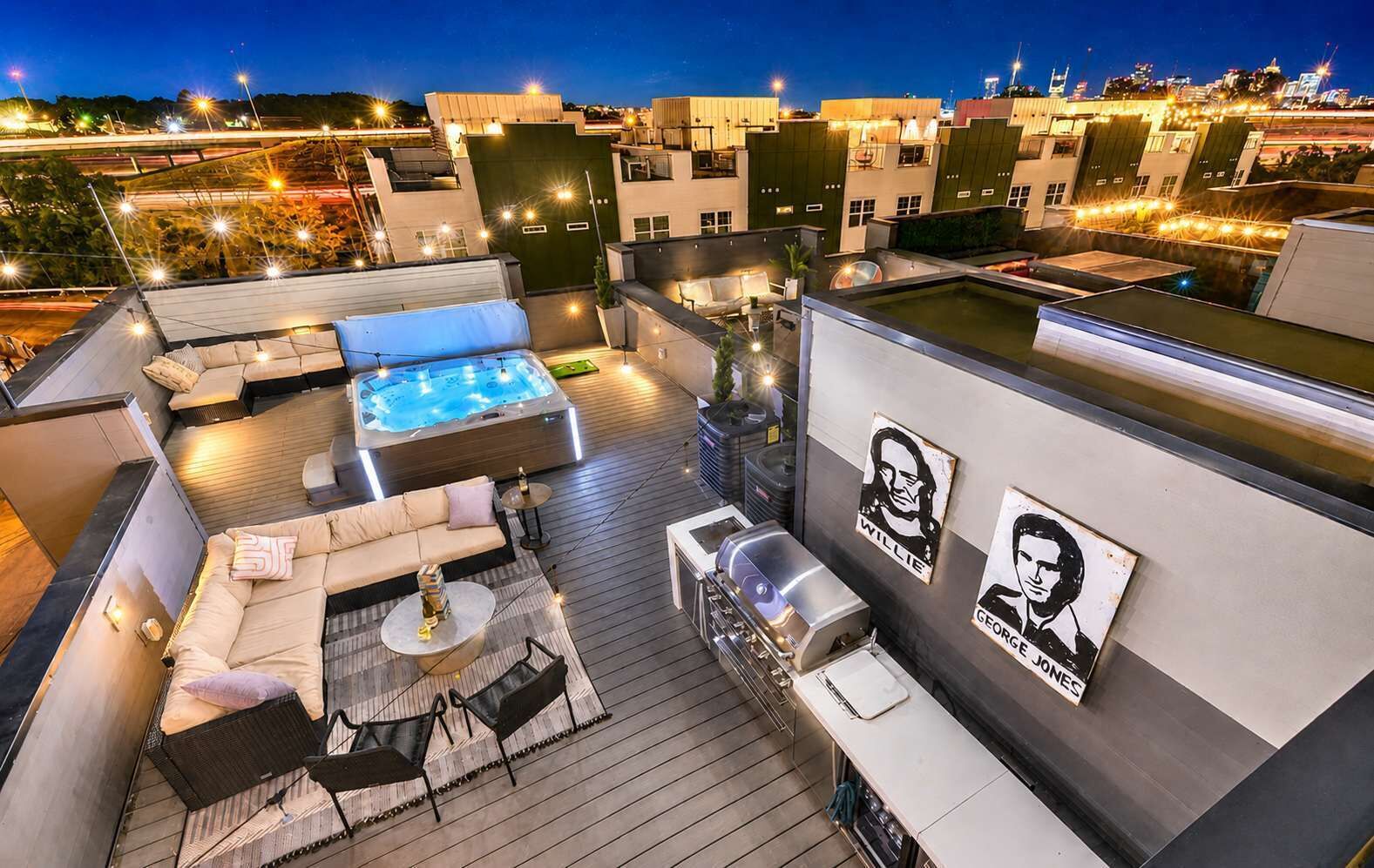 A rooftop terrace with a hot tub, seating area, and barbecue grill.