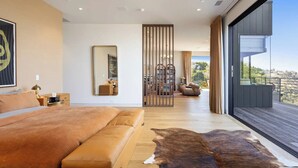 Un dormitorio moderno con una cama grande, un separador de madera y vistas al exterior.