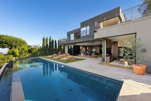 Una casa moderna con piscina, mobiliario exterior y un jardín bien cuidado.