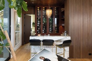 Una cocina moderna con encimera de mármol, armarios de madera y una estantería para vinos.