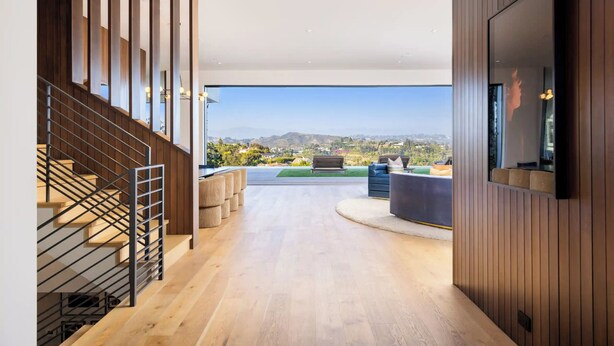 Un interior moderno con una escalera, un televisor de pantalla plana y vistas al exterior.