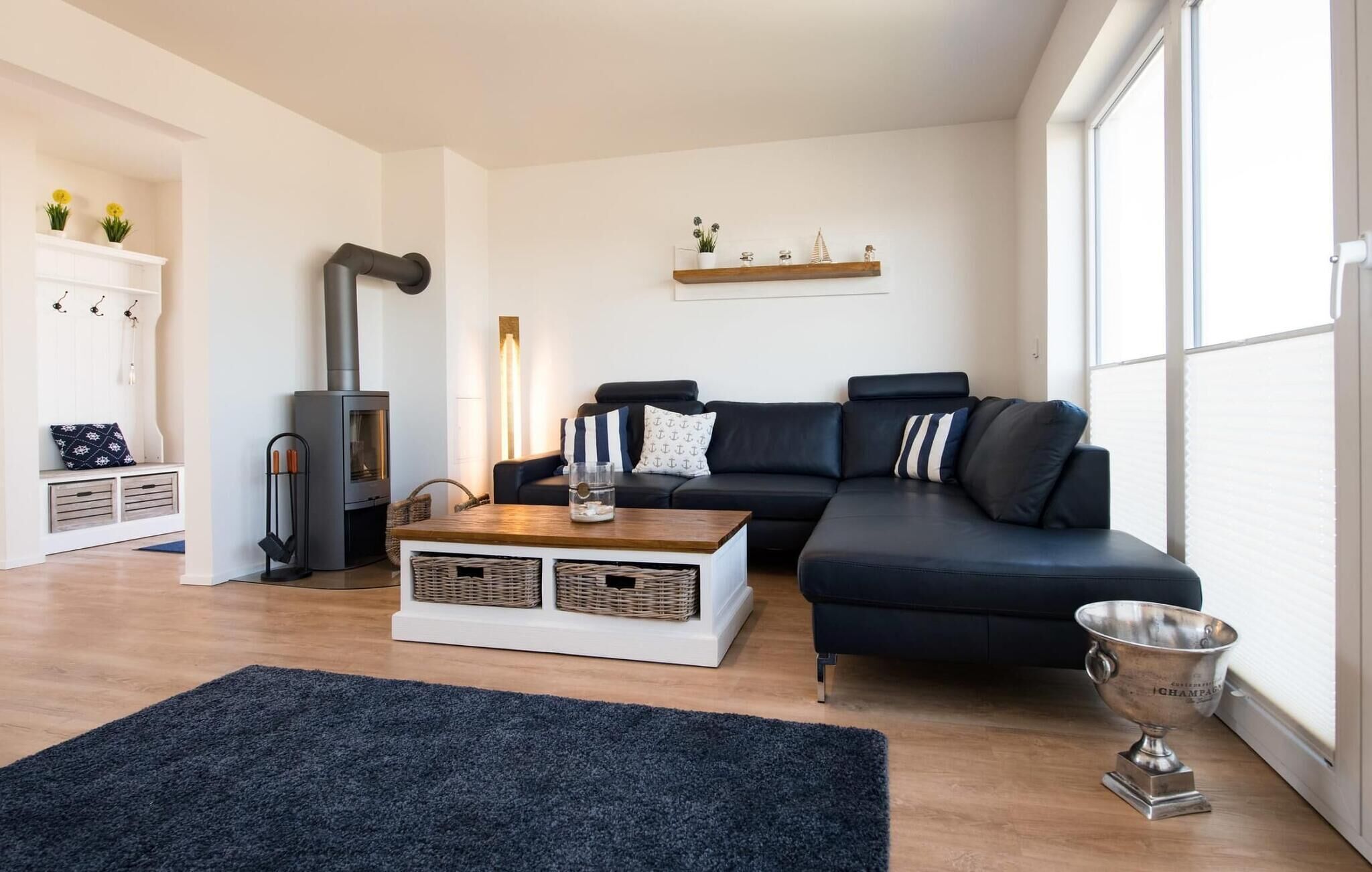 Un salon moderne avec un canapé en cuir noir, une table basse en bois, une cheminée et une grande fenêtre laissant entrer la lumière naturelle.