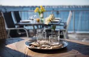 A dining table with a tray of nuts and two glasses on a wooden deck with a view of the sea. - Pet friendly apartment in Olpenitz (Olpenitz)