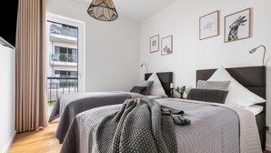 Ein modernes Schlafzimmer mit zwei Betten, einem Balkon und Blick auf die Stadt.