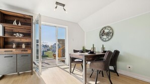 Une cuisine moderne avec un mur d’accent en bois, un coin repas avec une table et des chaises, et une grande fenêtre offrant une vue sur le quartier.