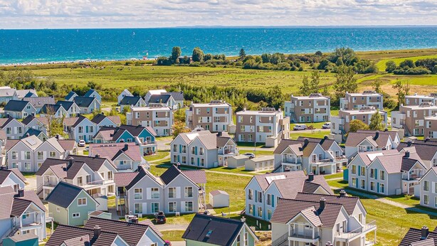 Un quartier résidentiel avec des maisons modernes, une vue dégagée sur la mer et un paysage verdoyant bien entretenu.