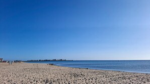 Une vaste plage de sable fin, sous un ciel bleu et dégagé.