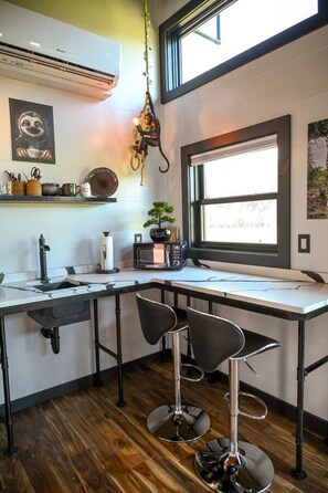 A modern kitchen with a built-in microwave, a sink, and two bar stools.