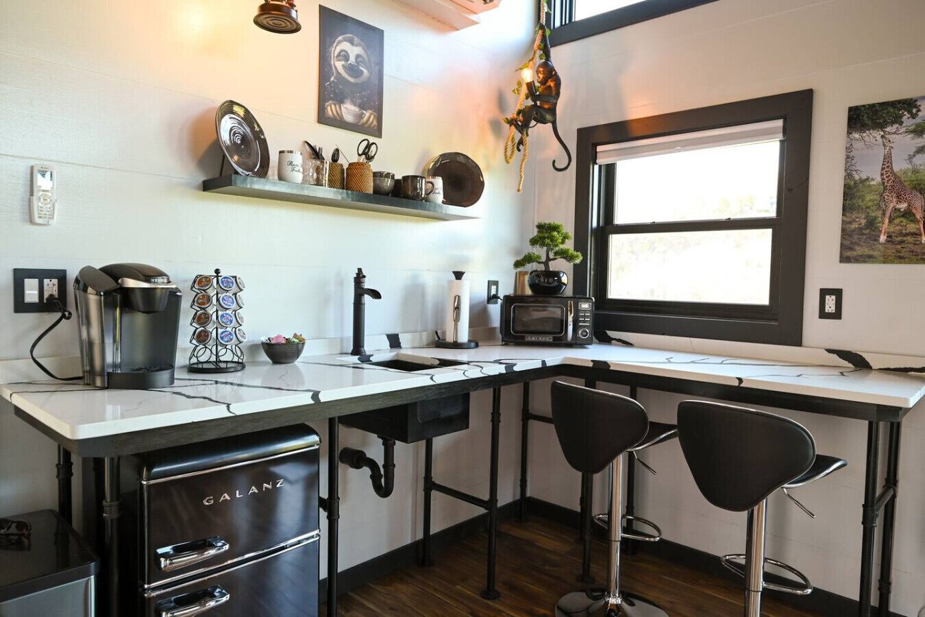 A modern kitchen with a coffee maker, microwave, and bar stools.
