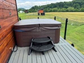Un bain à remous sur une terrasse en bois, avec vue sur un paysage rural.