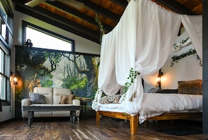 A room with a bed under a canopy, a sofa, and a mural of a forest. - Tarzan And Jane Treehouse. Hot tub. Riverfront (Sevierville)