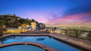 A rooftop pool with a view of the city at sunset.