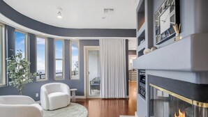 A modern living room with a fireplace, large windows, and a view of the outdoors.