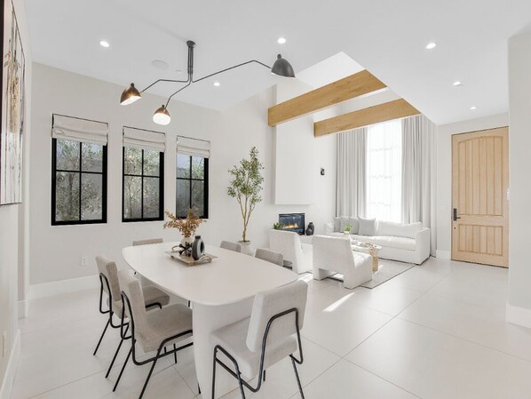 Una sala moderna con un sofá blanco, una mesa de comedor con sillas y una chimenea.