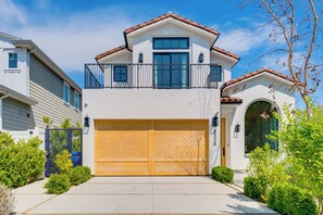 A two-story house with a large garage door, a balcony, and a well-maintained front yard.