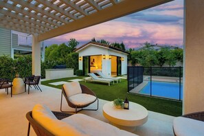 Un patio exterior con mobiliario, una piscina y una casa pequeña con vista a la piscina.