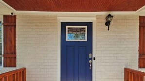 A blue door with a window, a welcome mat, and a wooden railing. - Charming 3-bedroom house in welcoming Hollywood/Meggett, SC. (Meggett)