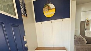 A hallway with a blue door, a bench, a welcome sign, and a patterned rug. - Charming 3-bedroom house in welcoming Hollywood/Meggett, SC. (Meggett)