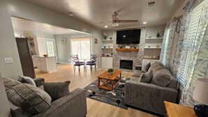 A modern living room with grey sofas, a wooden coffee table, and a TV mounted on the wall. - Charming 3-bedroom house in welcoming Hollywood/Meggett, SC. (Meggett)