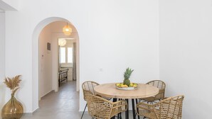 A dining area with a round wooden table, four wicker chairs, and a bowl of fruit.
